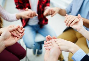 Four adults holding hands in prayer
