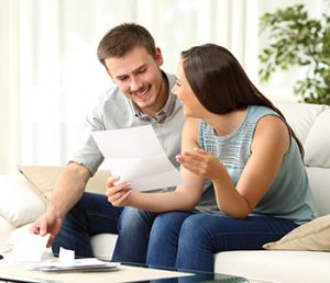 Smiling couple looking at sheet of paper, perhaps with a one-liner on it