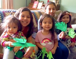 2 preschoolers, 2 older students holding paper palm branches for Palm Sunday