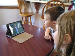 Middler brother and sister watch PowerPoint SS slideshow on laptop